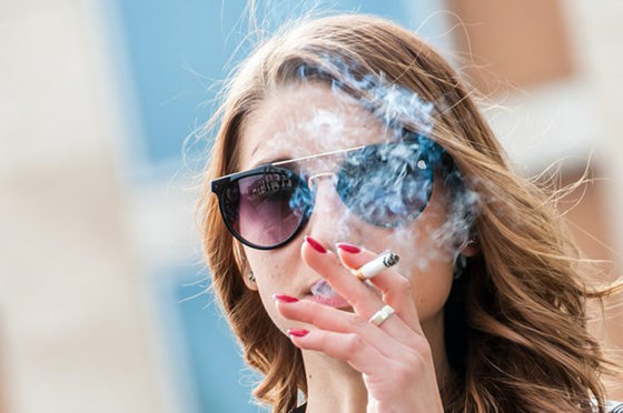 une femme qui fume une cigarette dehors